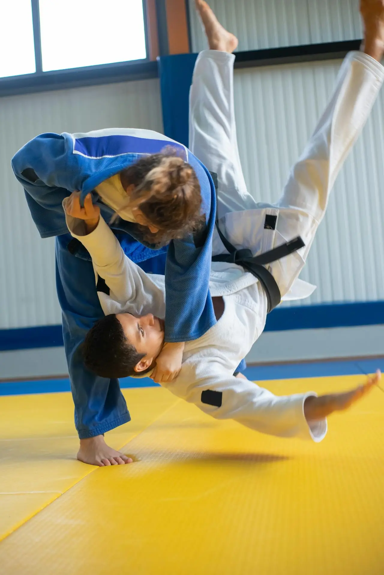 A female judoka throwing a male judoka to the ground